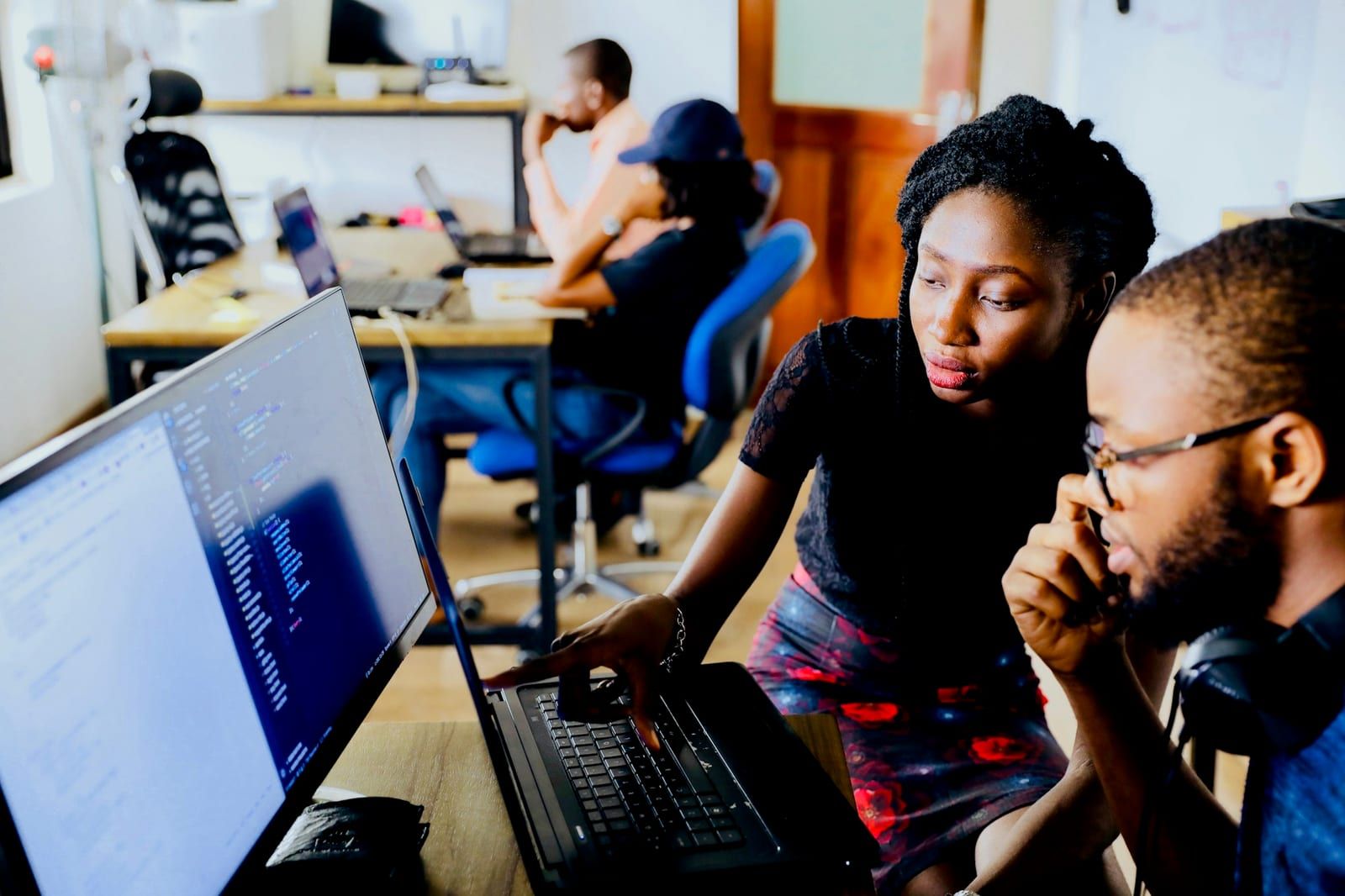 Two members of a technical team reviewing code together at a laptop