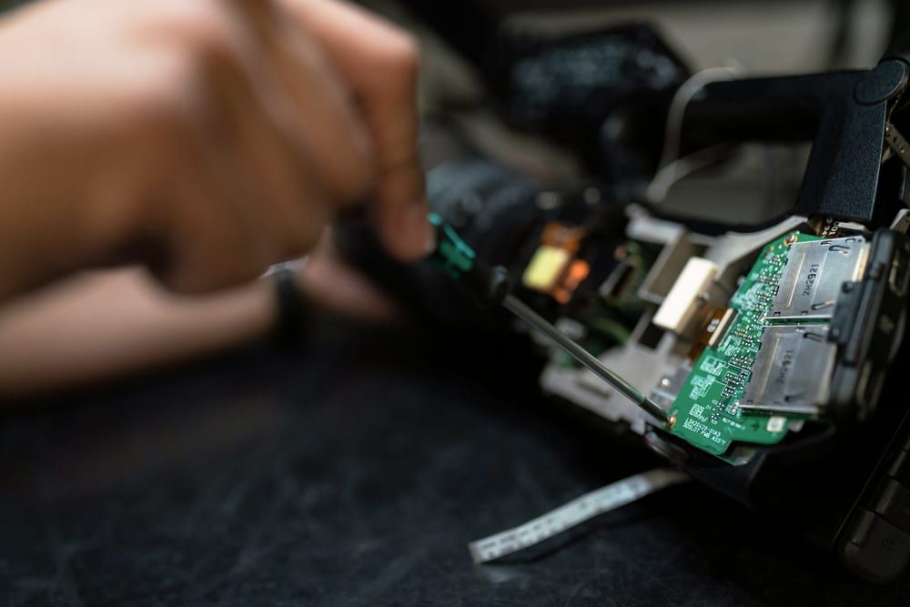 Hands working on the board of an opened device with a precision tool